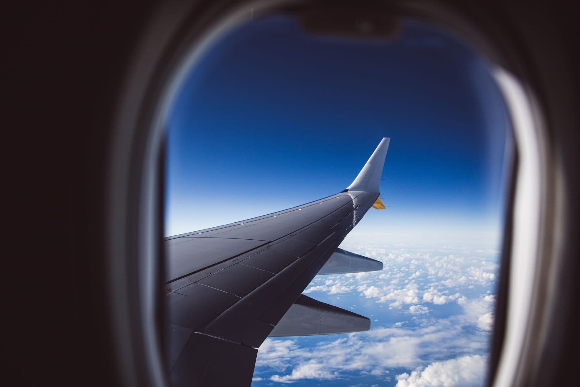 The wing of an aircraft above cloud, seen from a passenger window.